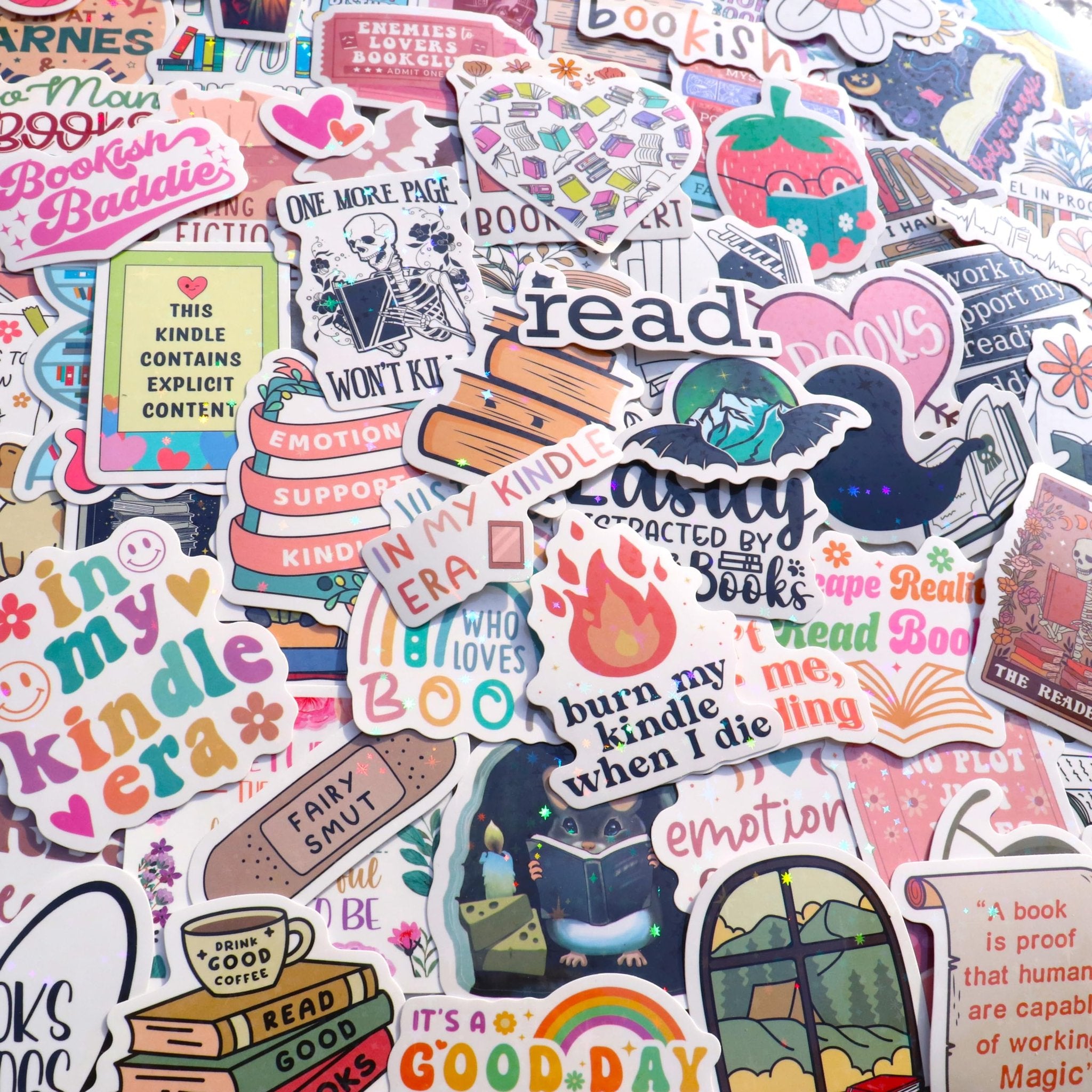 A flat lay of numerous book-themed vinyl stickers with holographic accents, featuring various designs like books, reading-related quotes, and cute characters.