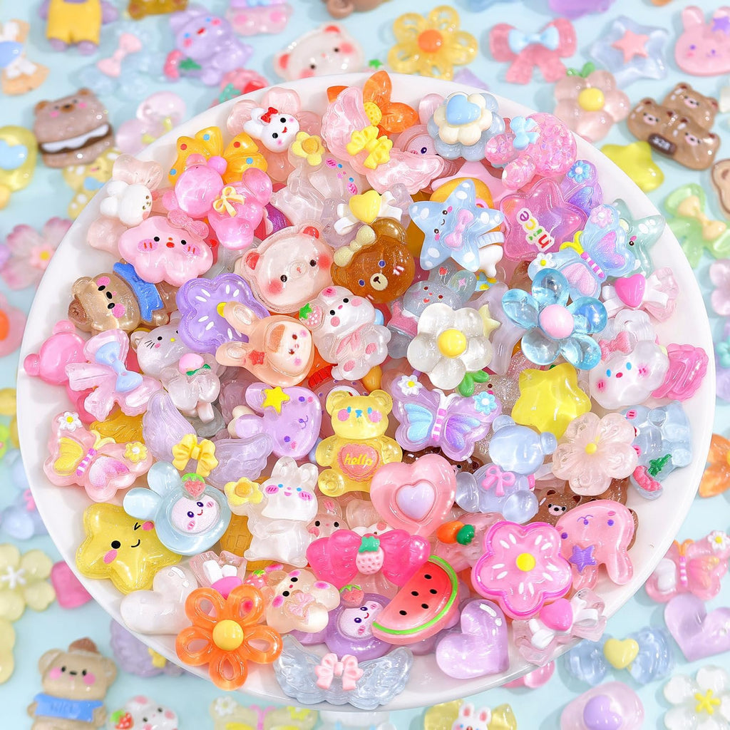 Assorted flatback resin kawaii charms including bears, flowers, stars, and fruit on a white plate, close-up view.
