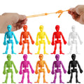 Hands stretching a toy skeleton by its arms, with a row of colorful toy skeletons below.