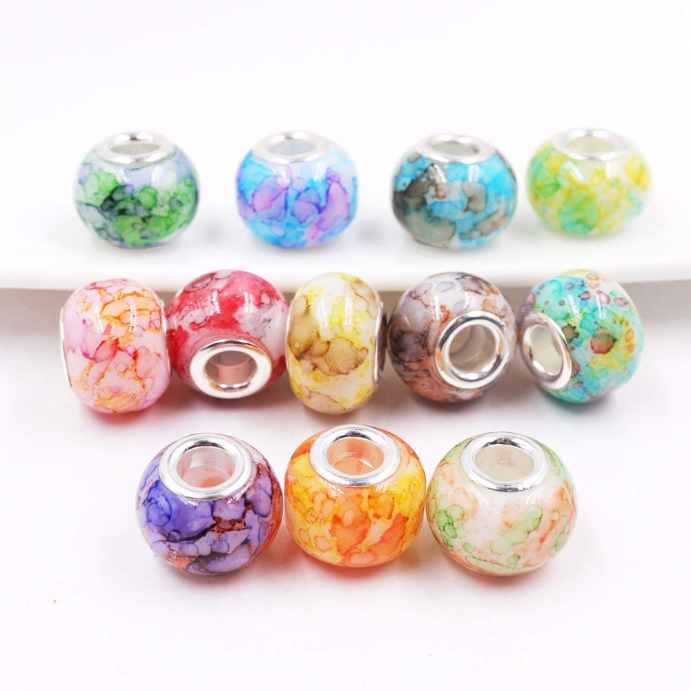 Assortment of ten colorful glass beads with brass cores arranged in three rows on a white surface.