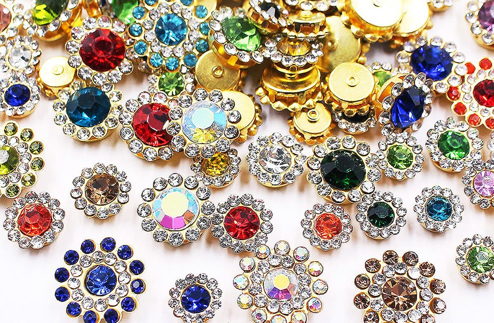 Assortment of sunflower-shaped sew-on rhinestones in various colors and sizes, featuring gold-tone settings and clear accent crystals.