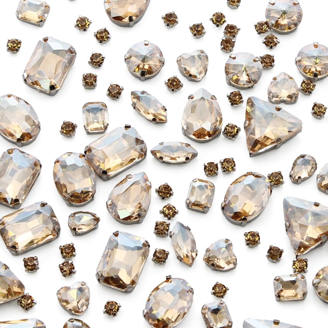Assortment of champagne colored glass rhinestones with silver claw settings in various shapes and sizes scattered on a white background.