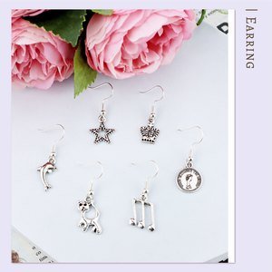 Six assorted Tibetan silver alloy charm pendants for jewelry making, including a dolphin, star, crown, cat, musical notes, and a coin.