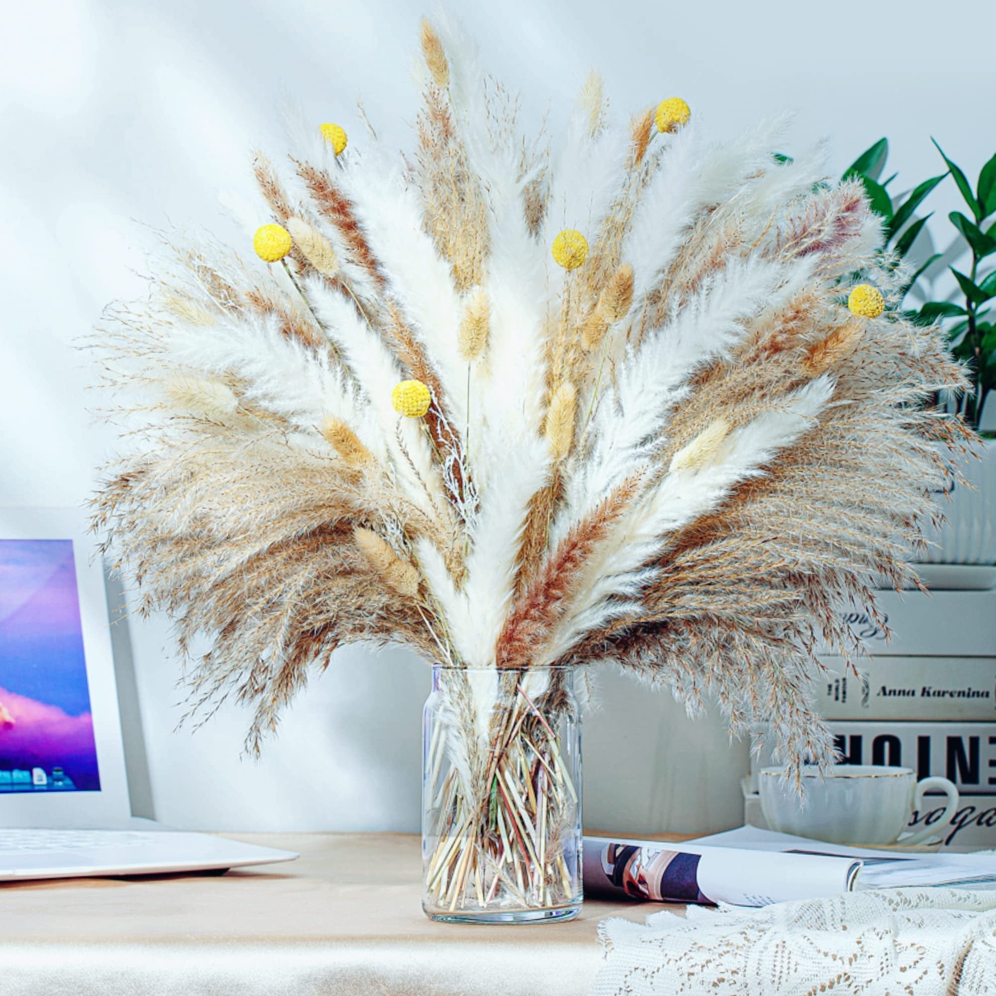 Boho dried pampas grass bouquet in a glass vase on a desk with a laptop and books