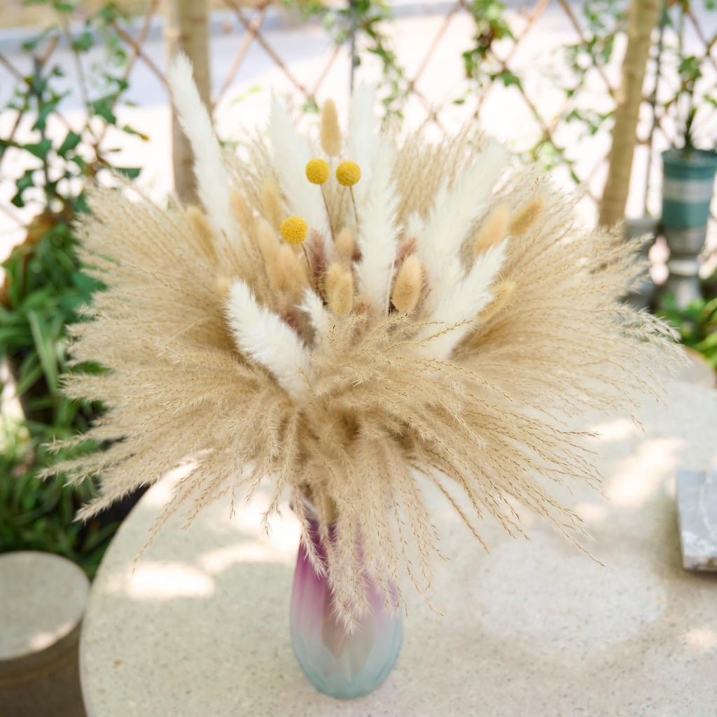 Boho dried pampas grass bouquet with yellow accents in a gradient vase on a textured table