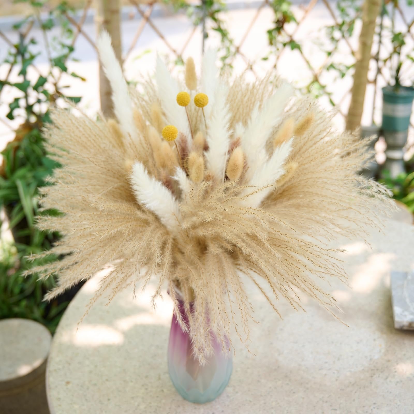 Boho dried pampas grass bouquet with yellow accents in a gradient vase on a textured table
