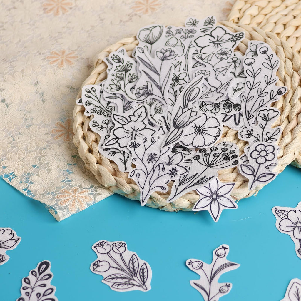 Assortment of pre-printed floral embroidery stabilizer sheets scattered on a blue surface and a woven coaster.