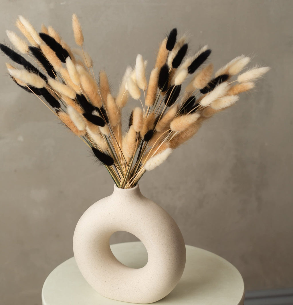 Bunny tails pampas grass in black, white, and natural brown in a modern donut-shaped vase.