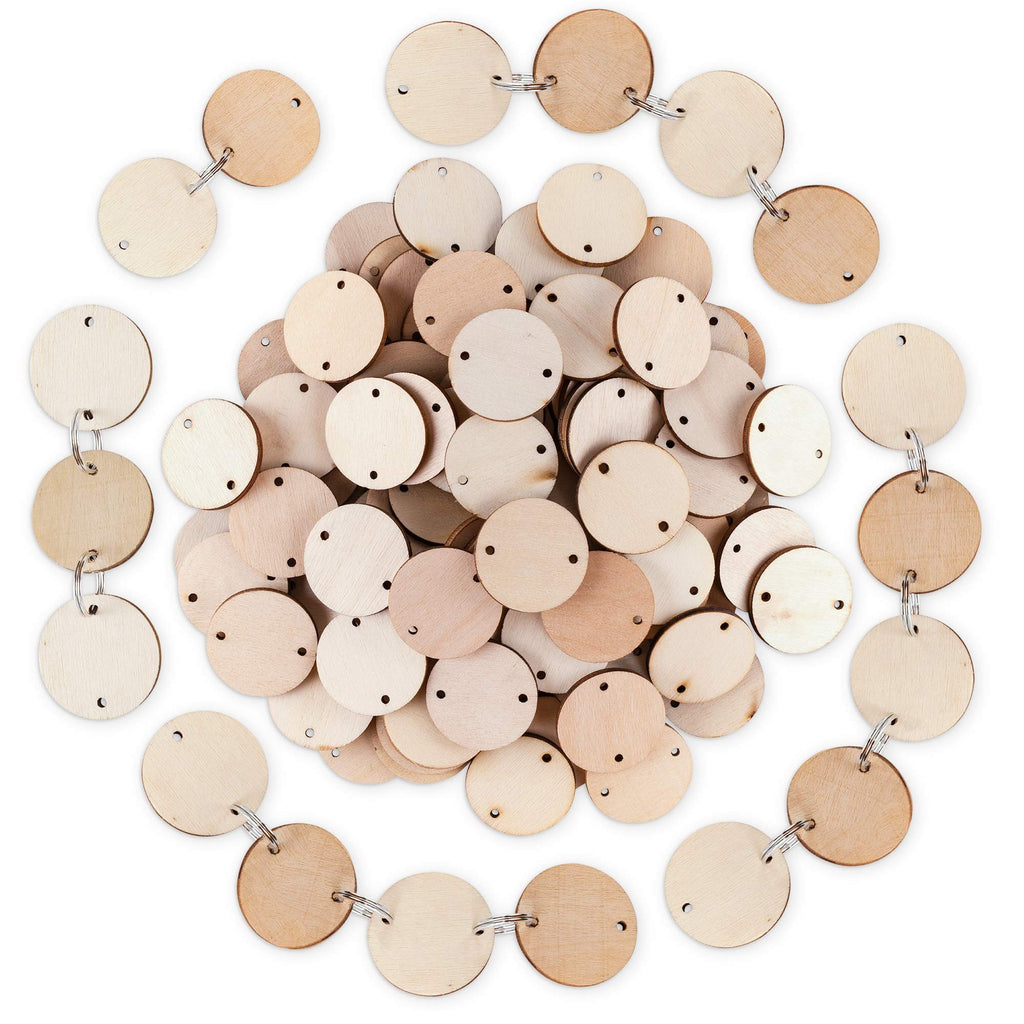 Pile of unfinished wooden circles with holes and attached key rings on a white background.