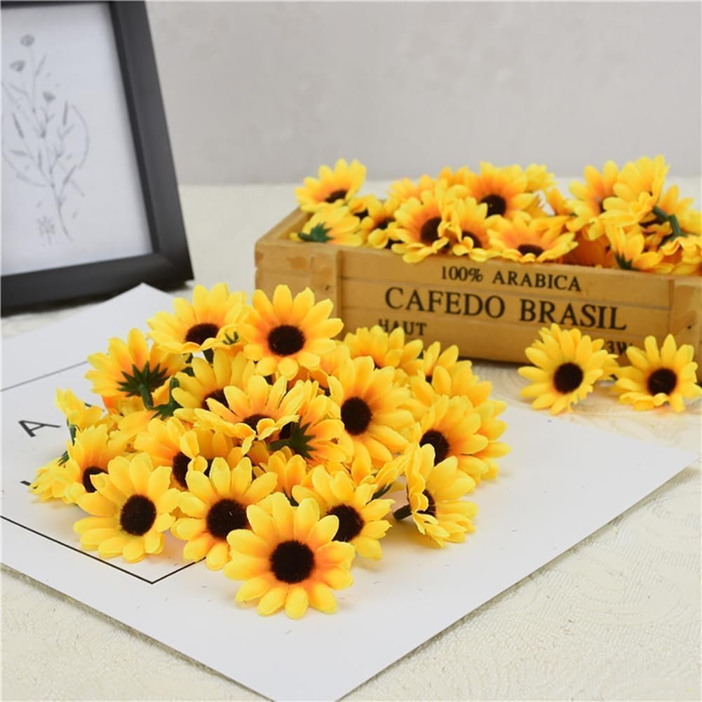 Pile of 100 yellow artificial sunflower heads scattered on white paper with a wooden crate in the background.