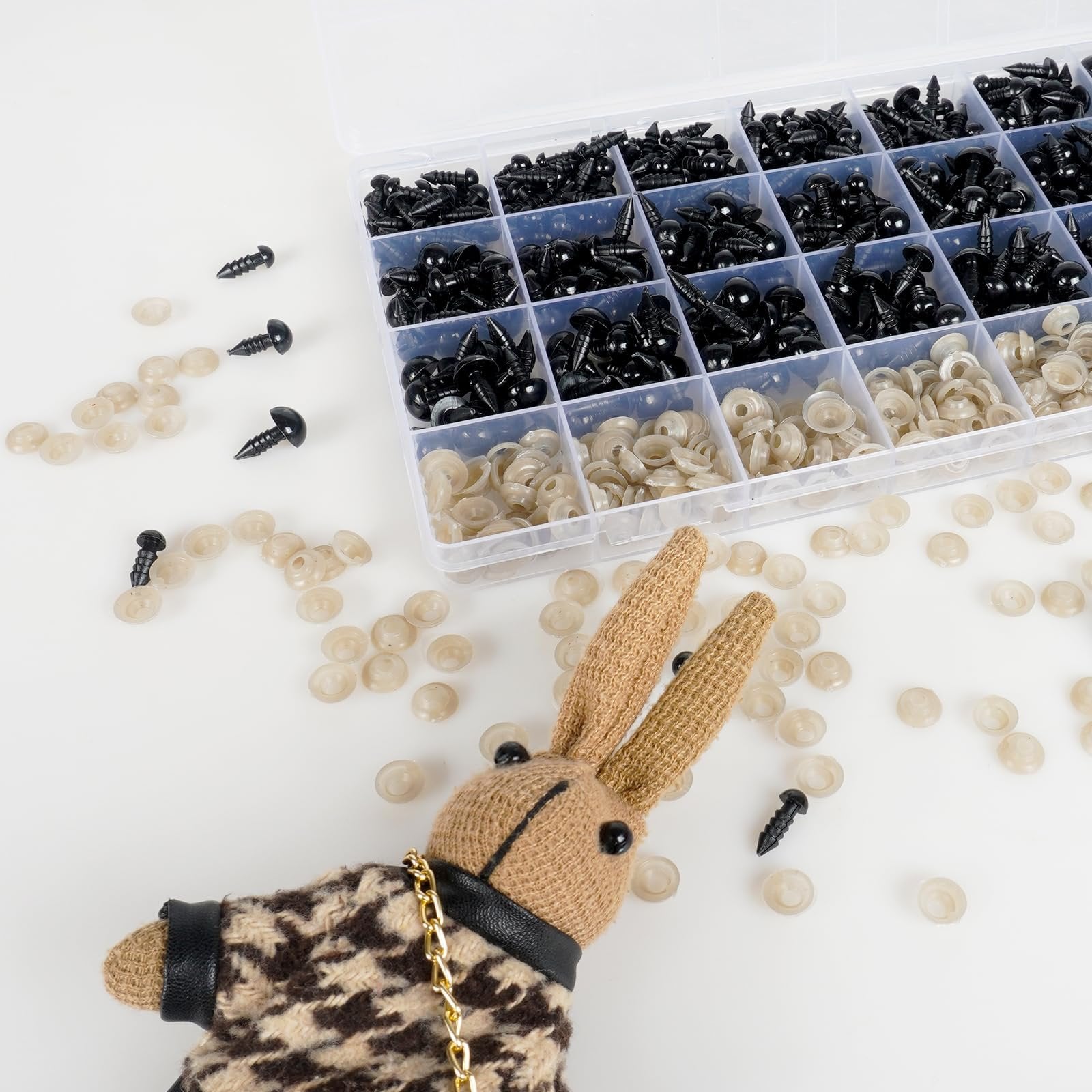 Amigurumi safety eyes and washers scattered around a knitted bunny with a patterned coat.