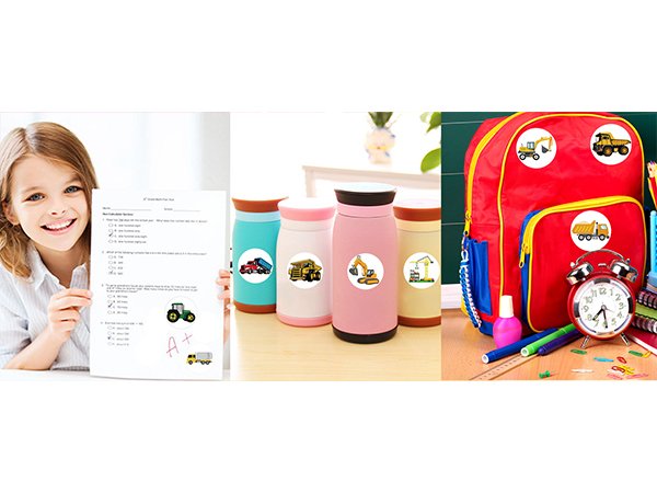 Smiling girl holds a test paper with construction vehicle stickers; water bottles and backpack decorated with stickers.