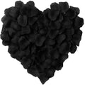 Heart shape made of black artificial silk rose petals on a white background