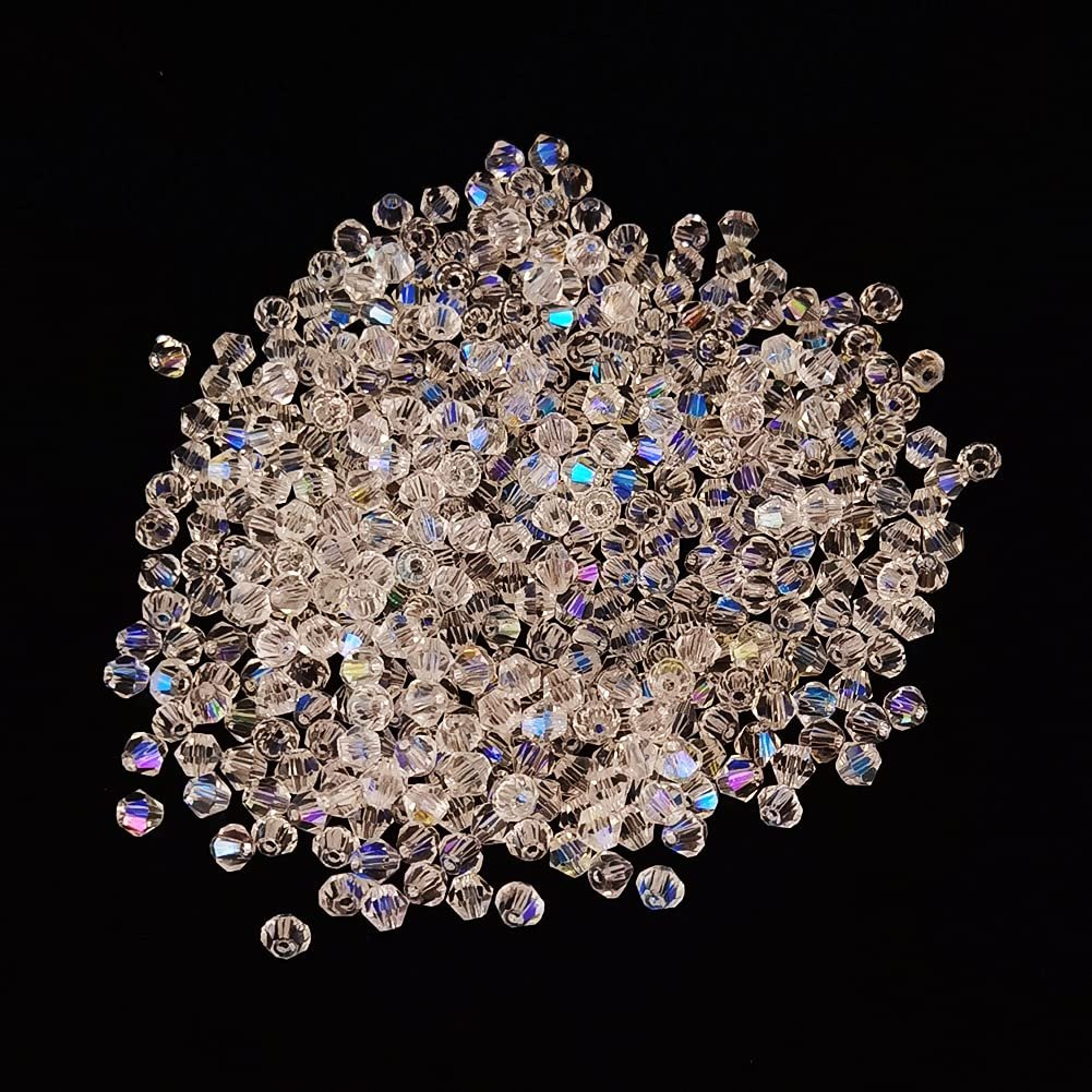 Pile of clear faceted crystal glass beads with AB finish on a black background, assorted sizes and shapes for jewelry making.