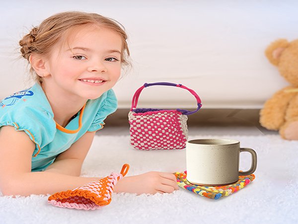 Smiling young girl lying on a rug with woven crafts and a mug on a coaster