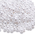 Pile of mixed-size white no-hole ABS plastic craft pearls on a white background.
