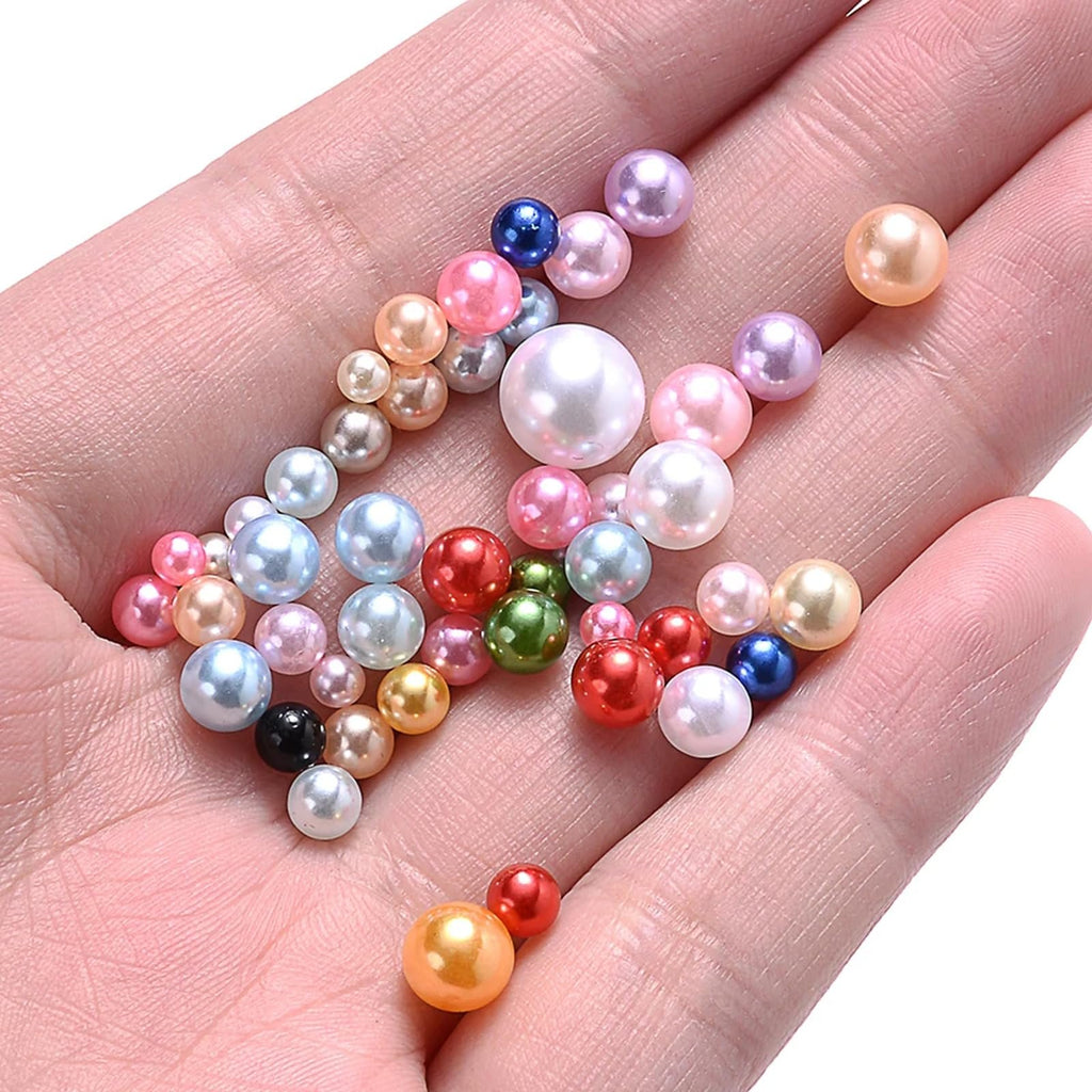Hand holding a collection of mixed-size, multi-colored no-hole pearls for crafts.