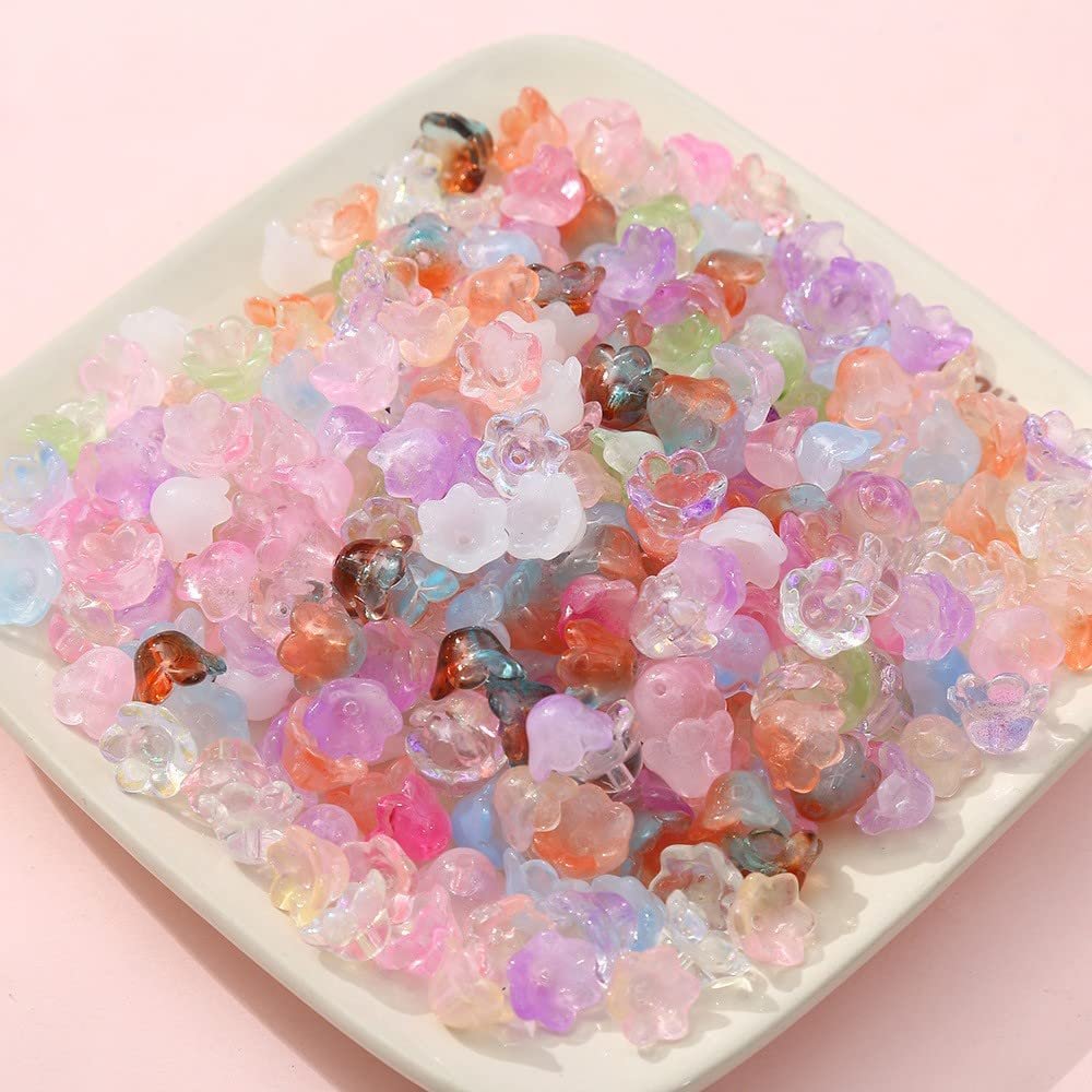 Pile of mixed color glass bellflower trumpet beads on a white square dish, close-up shot