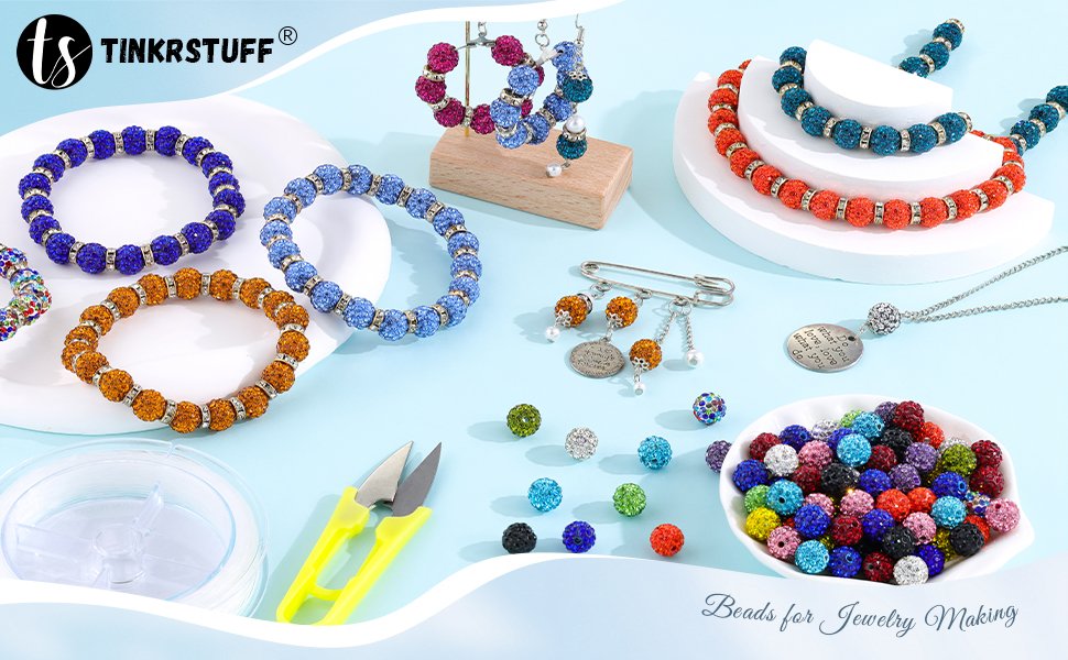 Assorted colorful rhinestone beads and jewelry making supplies including bracelets, necklaces, and tools on a light blue background.
