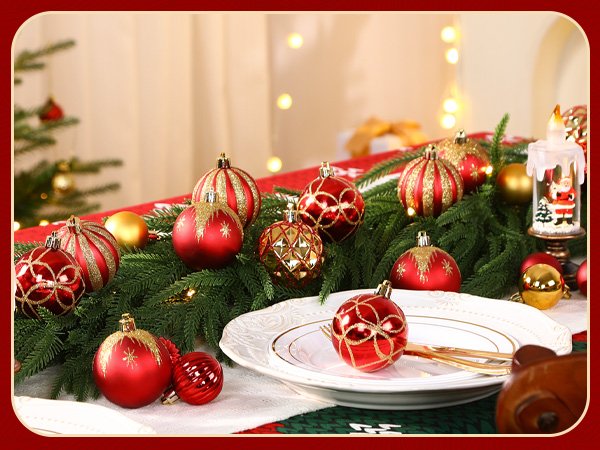 Christmas ornaments in red and gold arranged on a table with a white plate and greenery