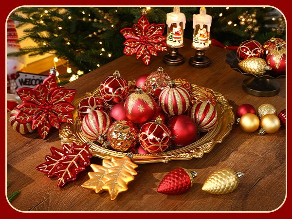 Assortment of red and gold Christmas ball ornaments and decorative pinecones on a wooden surface with a Christmas tree in the background.
