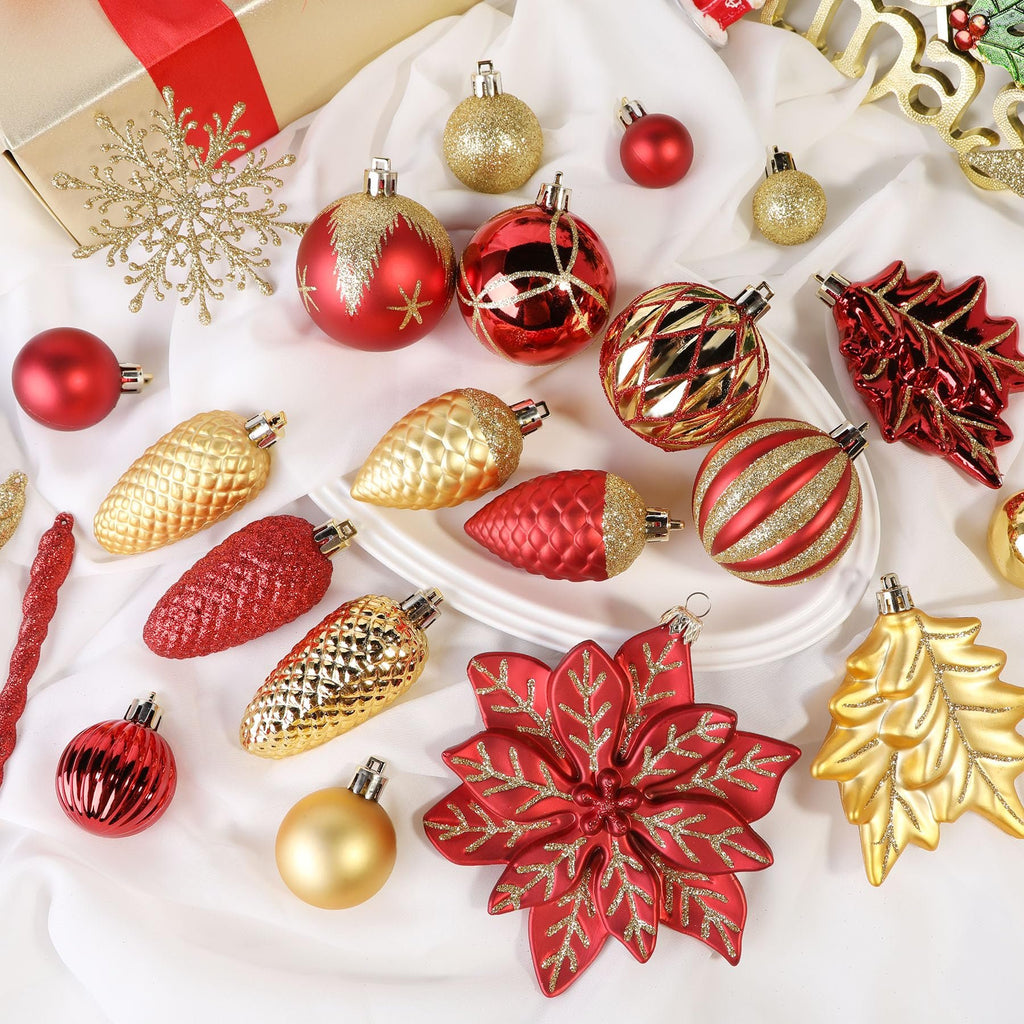 Assortment of red and gold Christmas ornaments including baubles, pinecones, icicles, a poinsettia, and a Christmas tree shape, arranged on a white cloth.