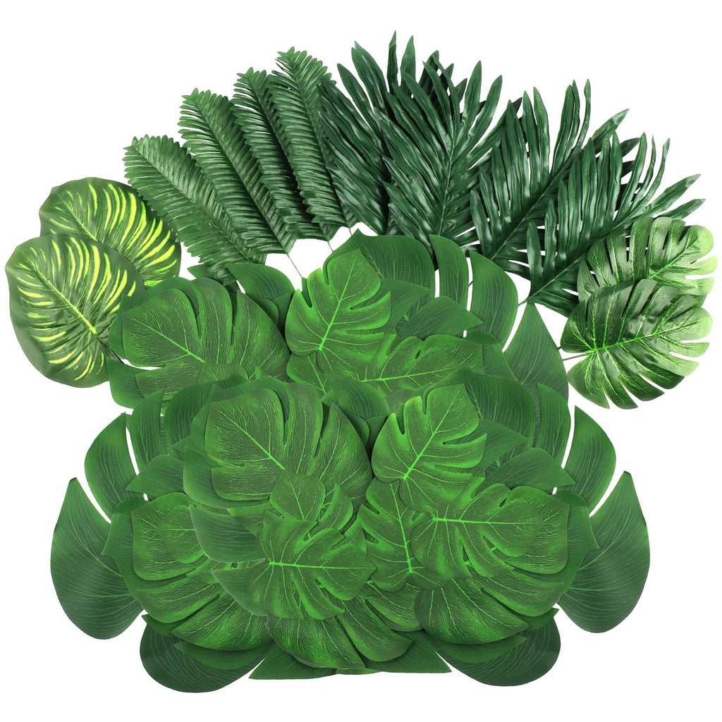 Assortment of artificial tropical leaves including monstera and palm varieties, arranged on a white background.