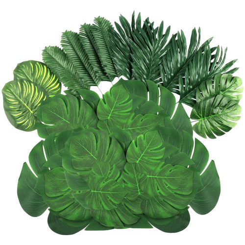 Assortment of artificial tropical leaves including monstera and palm varieties, arranged on a white background.