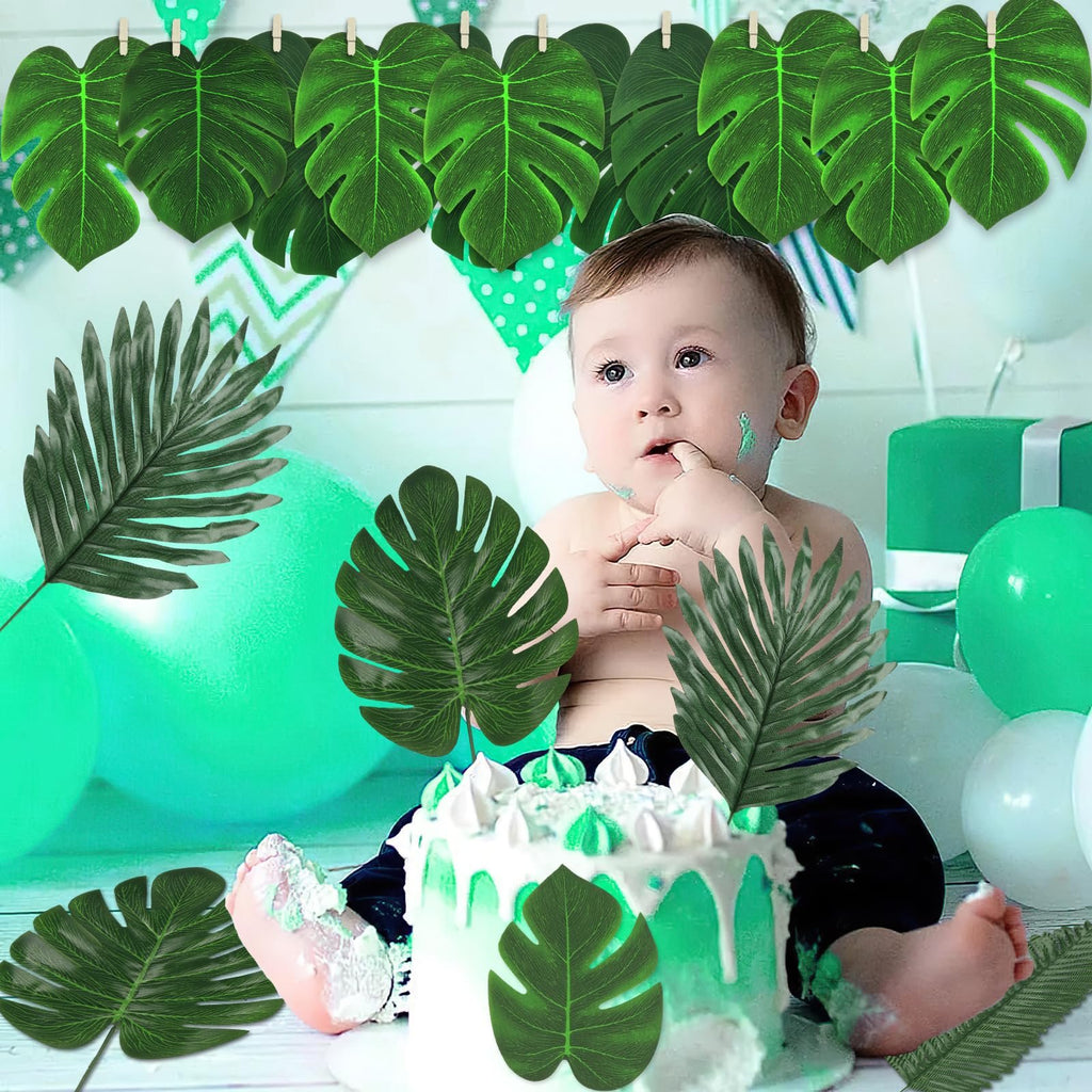 Baby sitting in front of a cake with artificial tropical leaves and balloons, celebrating a birthday.
