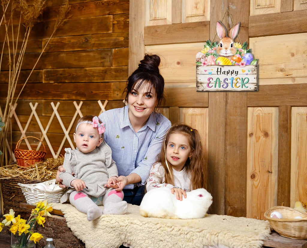 Woman and two children with a rabbit in a rustic setting, with an Easter door sign hanging on a wooden wall.