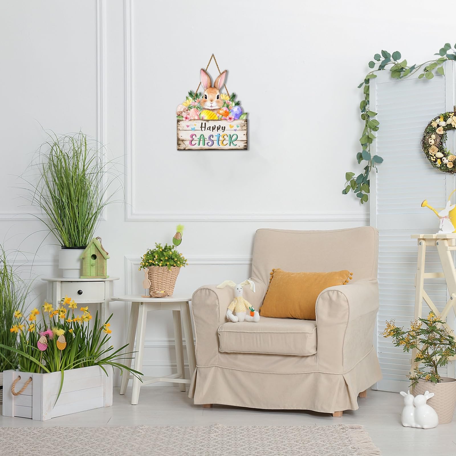 Easter door sign with bunny and eggs hanging on a white wall, next to a chair and plants.