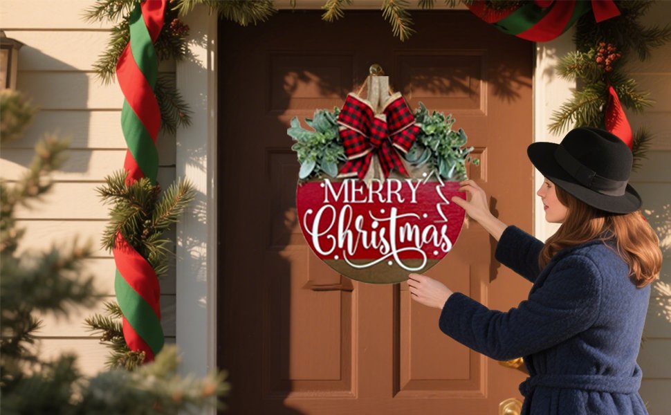 Woman hanging a round wooden Merry Christmas sign on a door decorated with garland