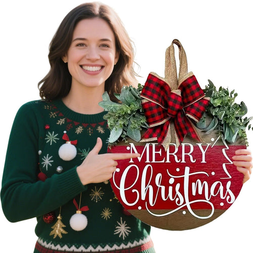 Woman in a festive sweater pointing to a round wooden Merry Christmas sign with a plaid bow and greenery