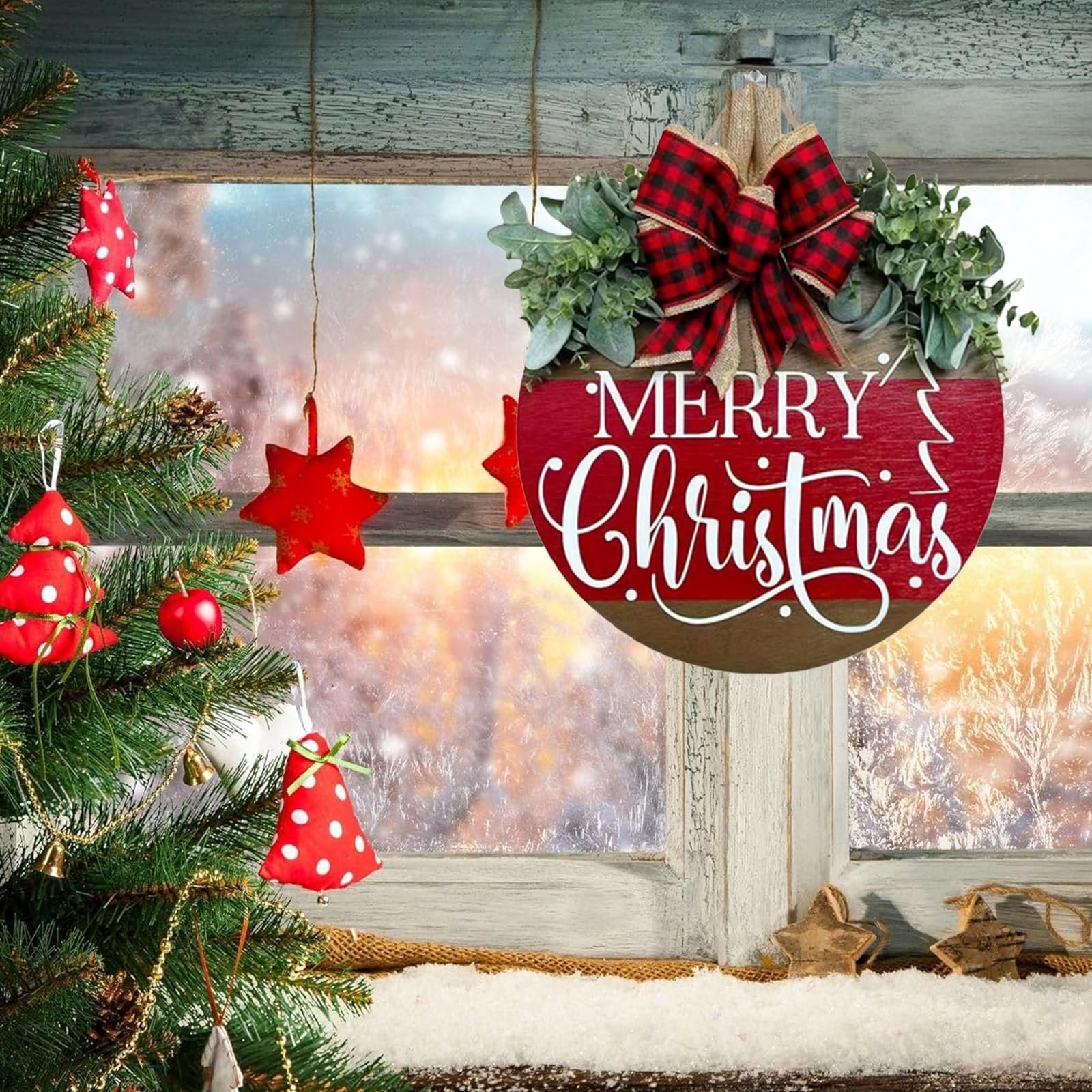 Round wooden Merry Christmas sign with red and black buffalo plaid bow and green eucalyptus leaves, hanging on a window with a snowy winter scene outside.