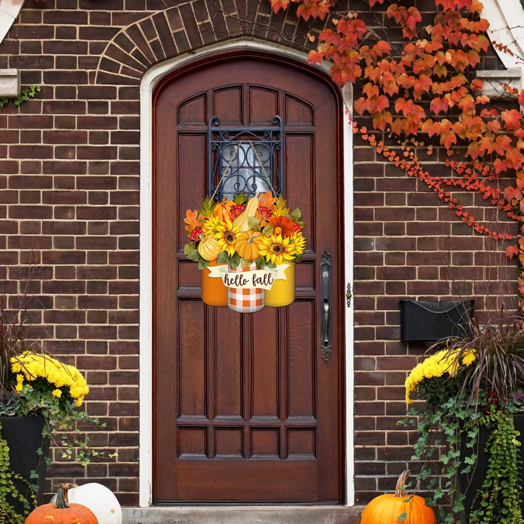 Fall welcome sign with sunflowers, pumpkins, and maple leaves hanging on a wooden door.