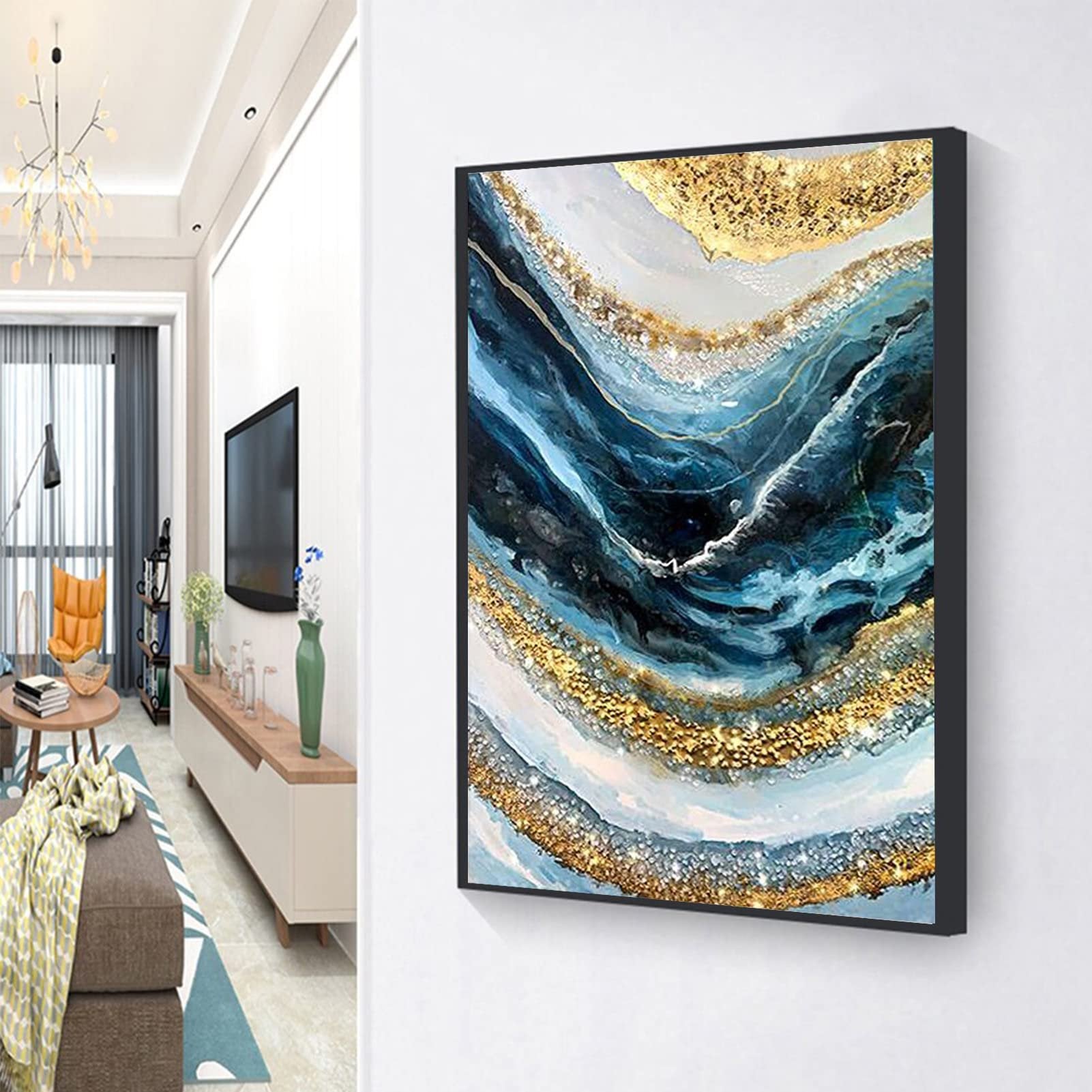 Abstract wave diamond painting with blue and gold colors, framed and hanging on a wall in a living room setting.