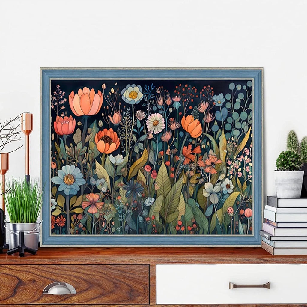 Framed floral diamond painting kit artwork displayed on a wooden dresser with plants and books.