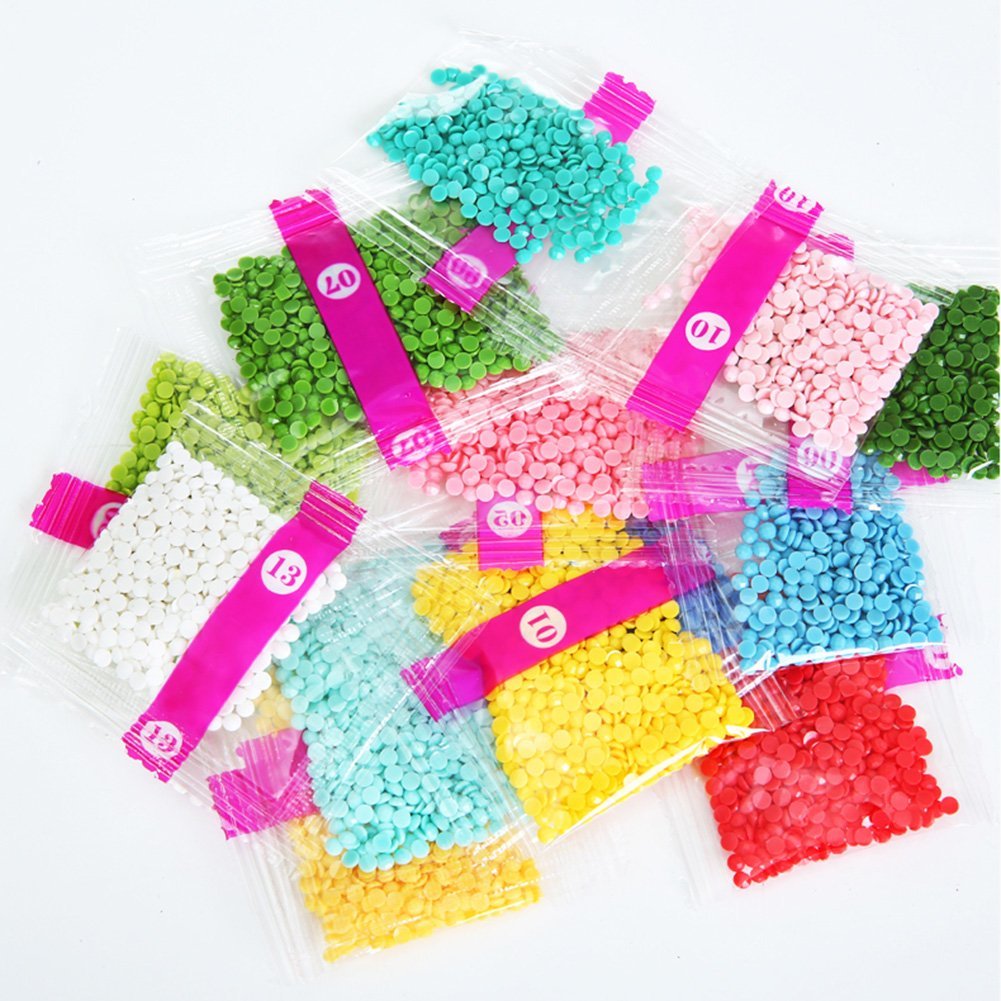 Diamond painting rhinestones in small clear bags with pink labels showing numbers, arranged in a pile.