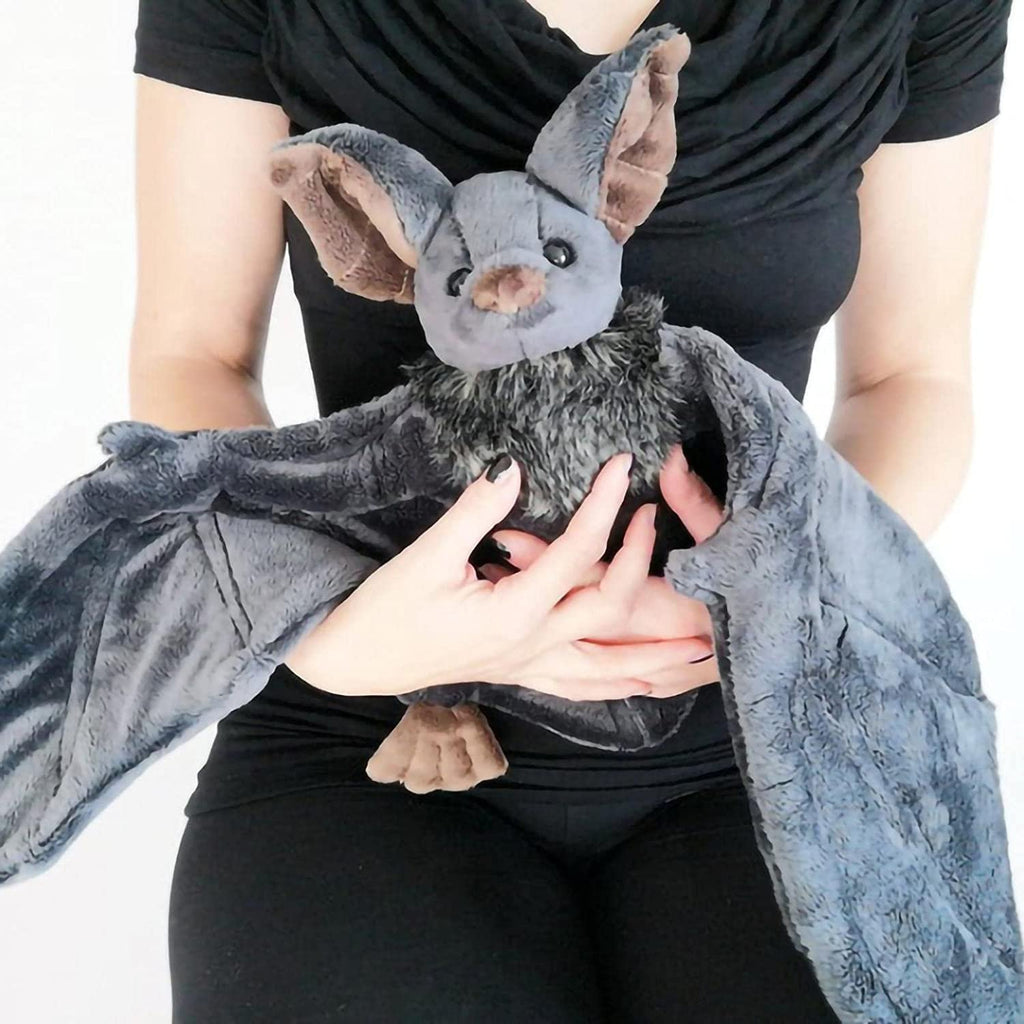 Person holding a gray plush bat with large wings and fluffy chest fur. The bat has brown inner ears and paws.