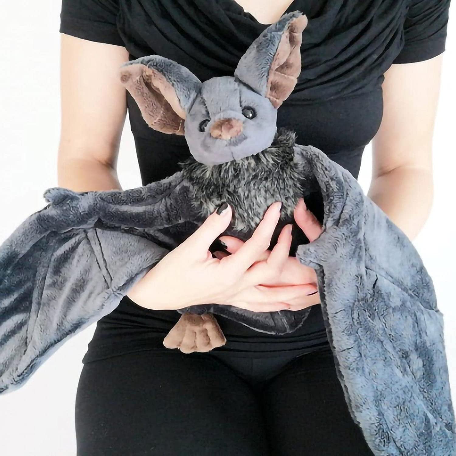 Person holding a gray plush bat with large wings and fluffy chest fur. The bat has brown inner ears and paws.