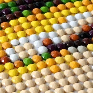 Close-up of a 5D diamond painting kit with colorful faceted resin gems arranged on a canvas.