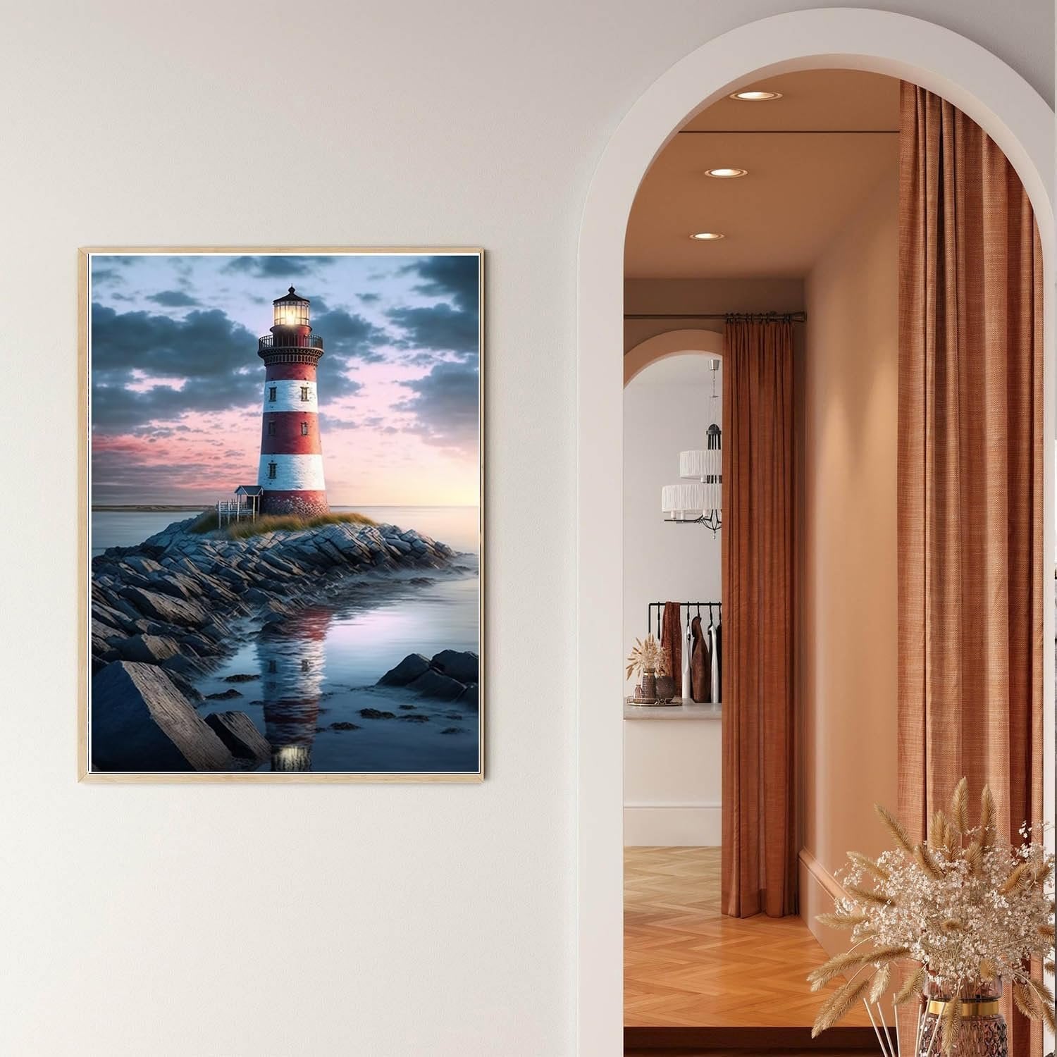 Framed diamond painting of a red and white lighthouse on a rocky shore at sunset, displayed on a wall.