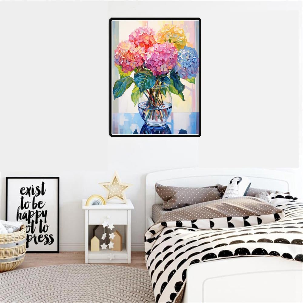 Diamond painting kit of colorful hydrangeas in a glass vase, displayed above a bed.