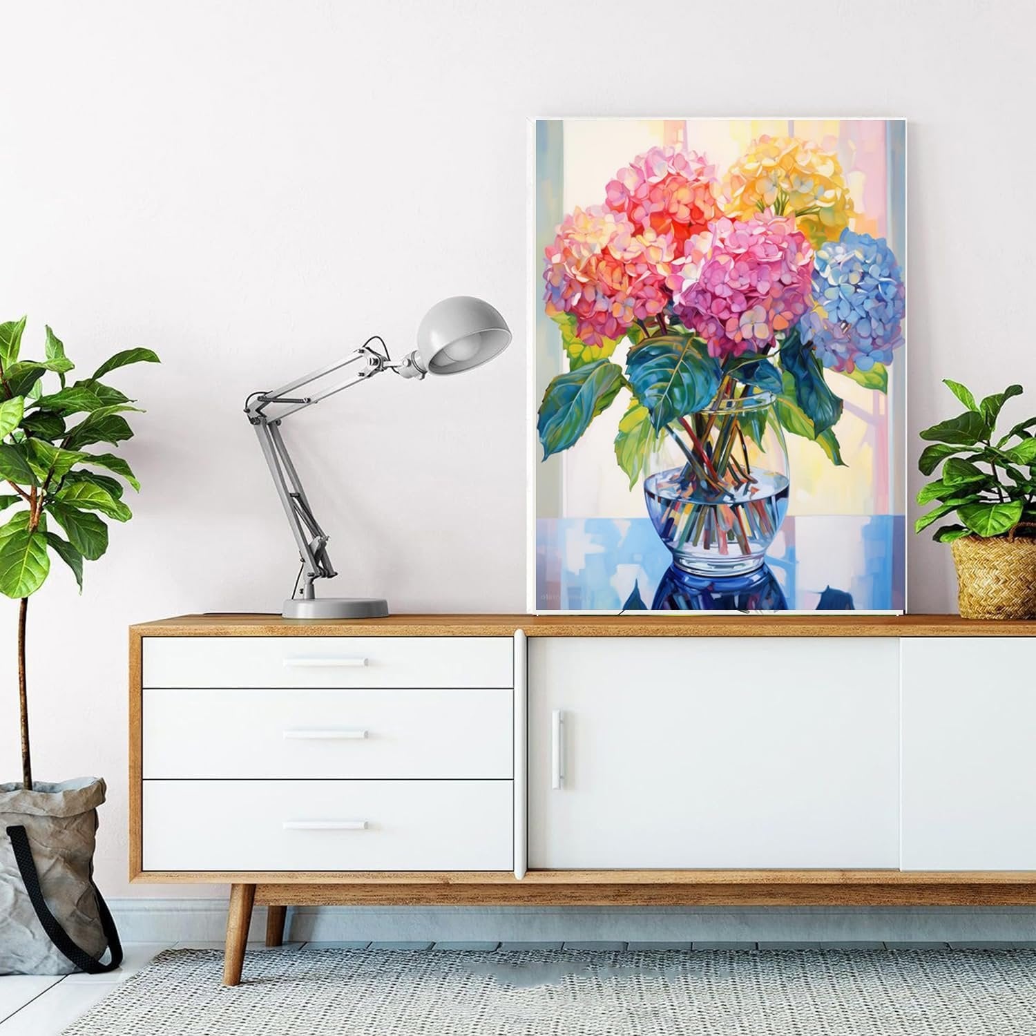 Diamond painting of colorful hydrangeas in a glass vase displayed on a dresser with plants and a lamp.