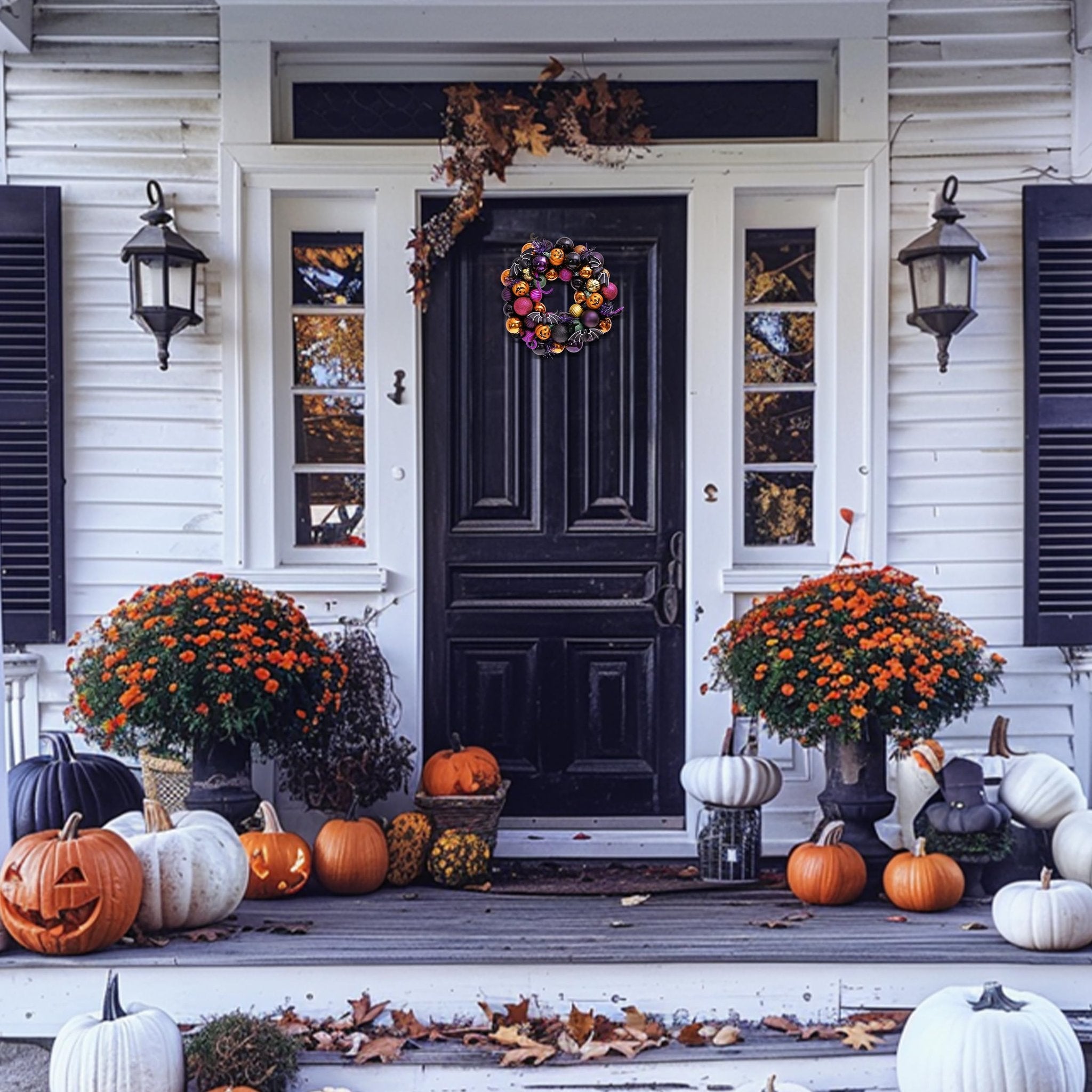 Halloween wreath with orange, purple, and black ornaments hanging on a dark front door, flanked by pumpkins and potted plants.