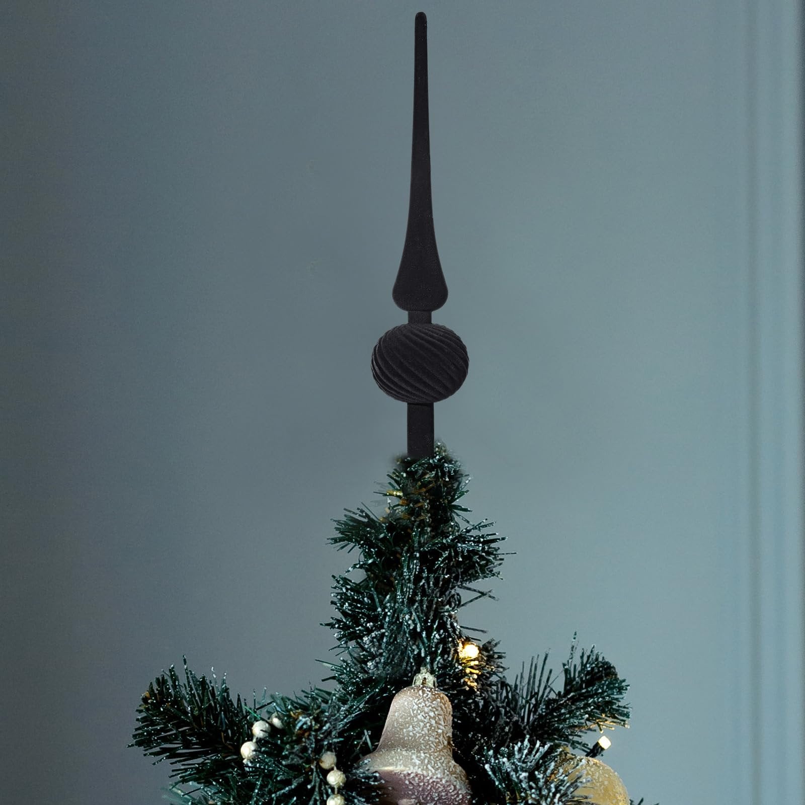 Black velvet finial Christmas tree topper with a spherical ornament, placed on top of a decorated evergreen tree.