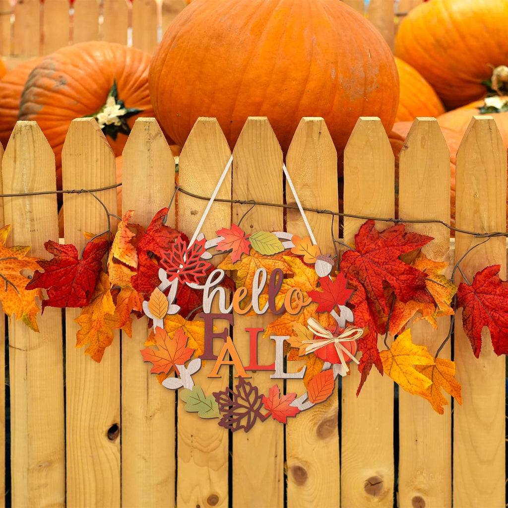 Wooden fall sign with 'hello FALL' text and autumn leaves, hanging on a wooden fence with pumpkins in the background.