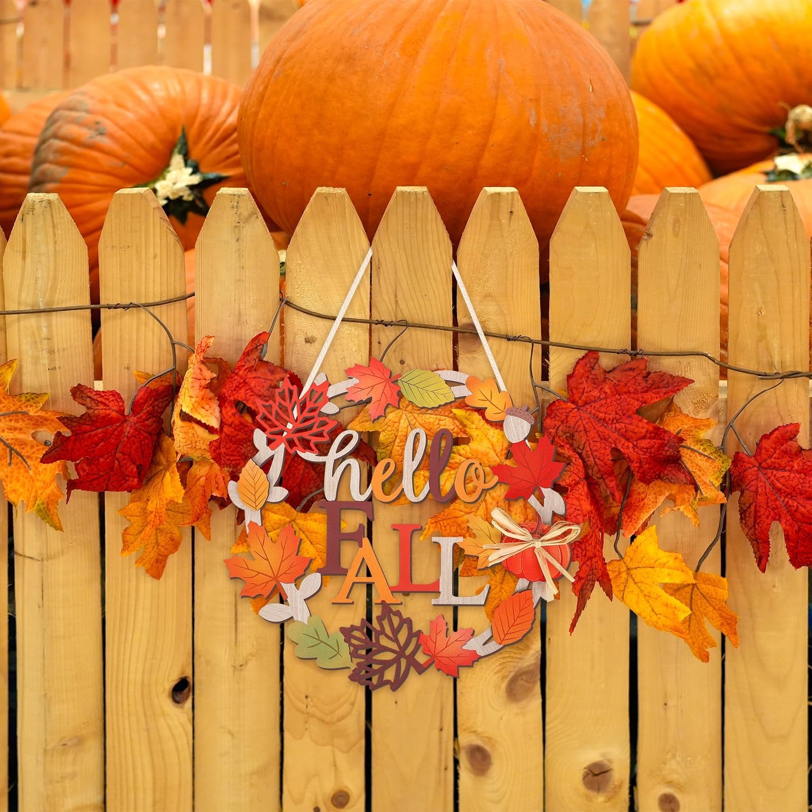 Wooden fall sign with 'hello FALL' text and autumn leaves, hanging on a wooden fence with pumpkins in the background.
