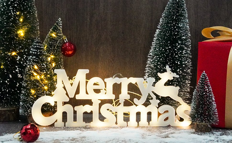 Lighted 'Merry Christmas' sign with reindeer, surrounded by mini Christmas trees and red ornaments.