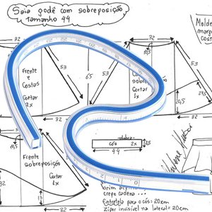 Flexible curve ruler laid over sewing pattern diagrams with measurements and annotations.